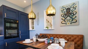 Une cuisine moderne avec des meubles bleus, une table à manger en bois et un banc en cuir marron.
