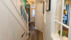 Un couloir avec un escalier, une porte et une fenêtre où se trouve une plante.
