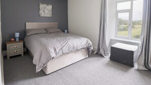 A bedroom with a bed, nightstand, lamp, and a window with curtains.