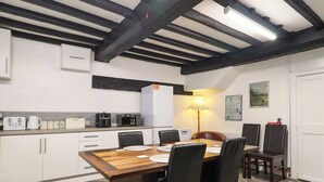 A modern kitchen with white cabinets, a wooden dining table, and black chairs.