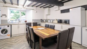 A modern kitchen with a wooden dining table, black chairs, and a built-in washing machine.