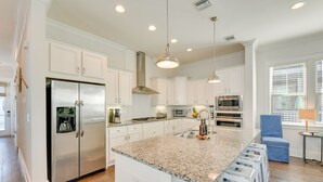 A modern kitchen with white cabinets, stainless steel appliances, granite countertops, and bar stools.