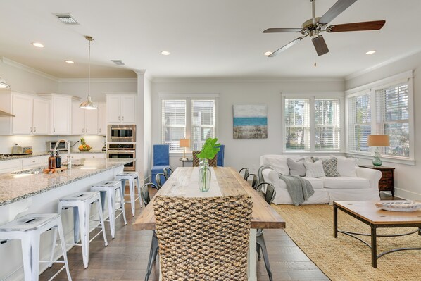 A spacious kitchen with white cabinets, a large island with bar stools, and a dining area with a wooden table and chairs.