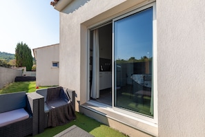 Une terrasse extérieure moderne, avec une porte-fenêtre coulissante donnant sur un espace cuisine.