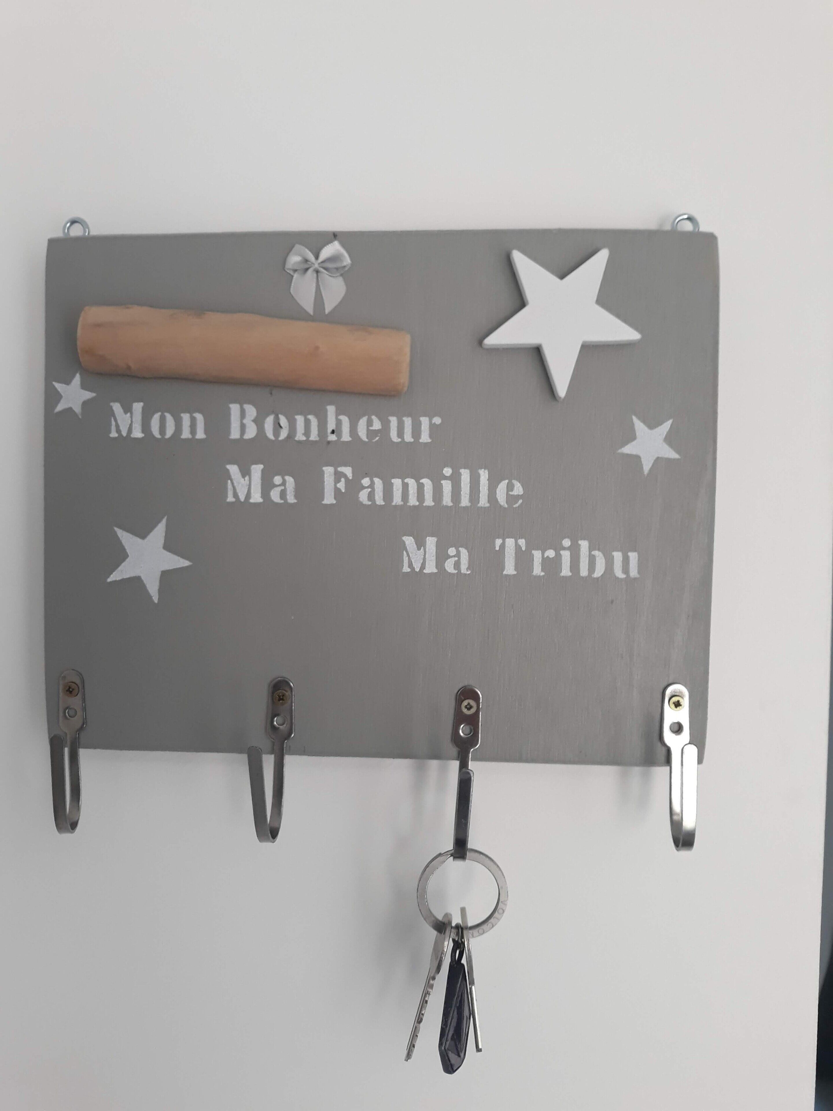 Un atril de pared para llaves con una placa que dice 'Mon Bonheur Ma Famille Ma Tribu' y estrellas decorativas.