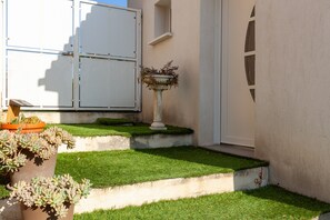 A well-maintained garden with a potted succulent plant, a decorative urn with plants, and a white door.