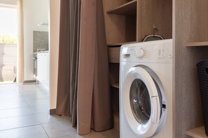 Une buanderie moderne équipée d’un lave-linge à chargement frontal, d’étagères en bois et d’une porte coulissante.