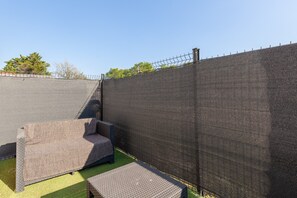 Un espace extérieur clos, aménagé avec des sièges et recouvert de gazon synthétique.