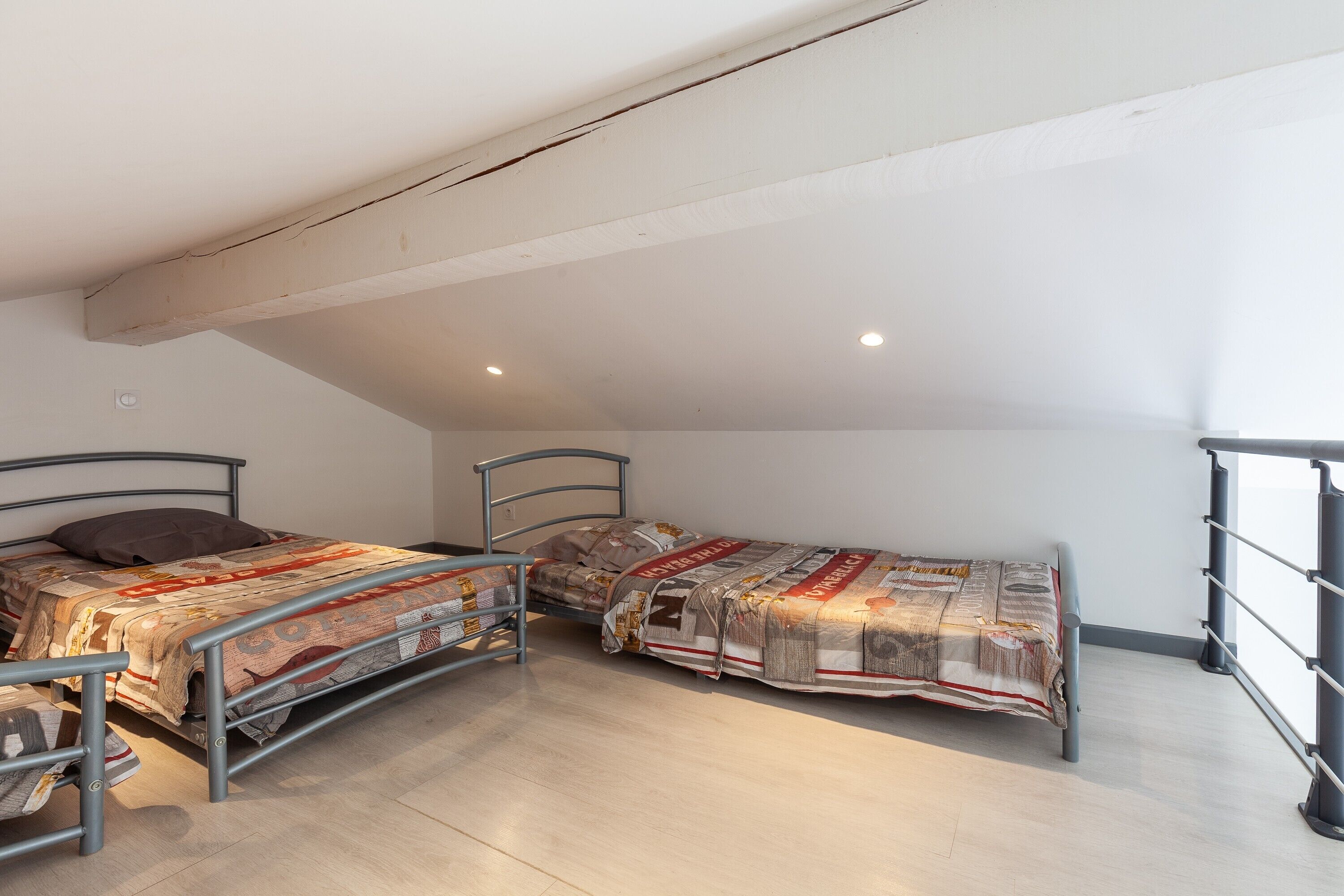 Ein Schlafsaalzimmer mit zwei Etagenbetten aus Metall, einem kleinen Schreibtisch und einem Fenster mit Metallgitter.