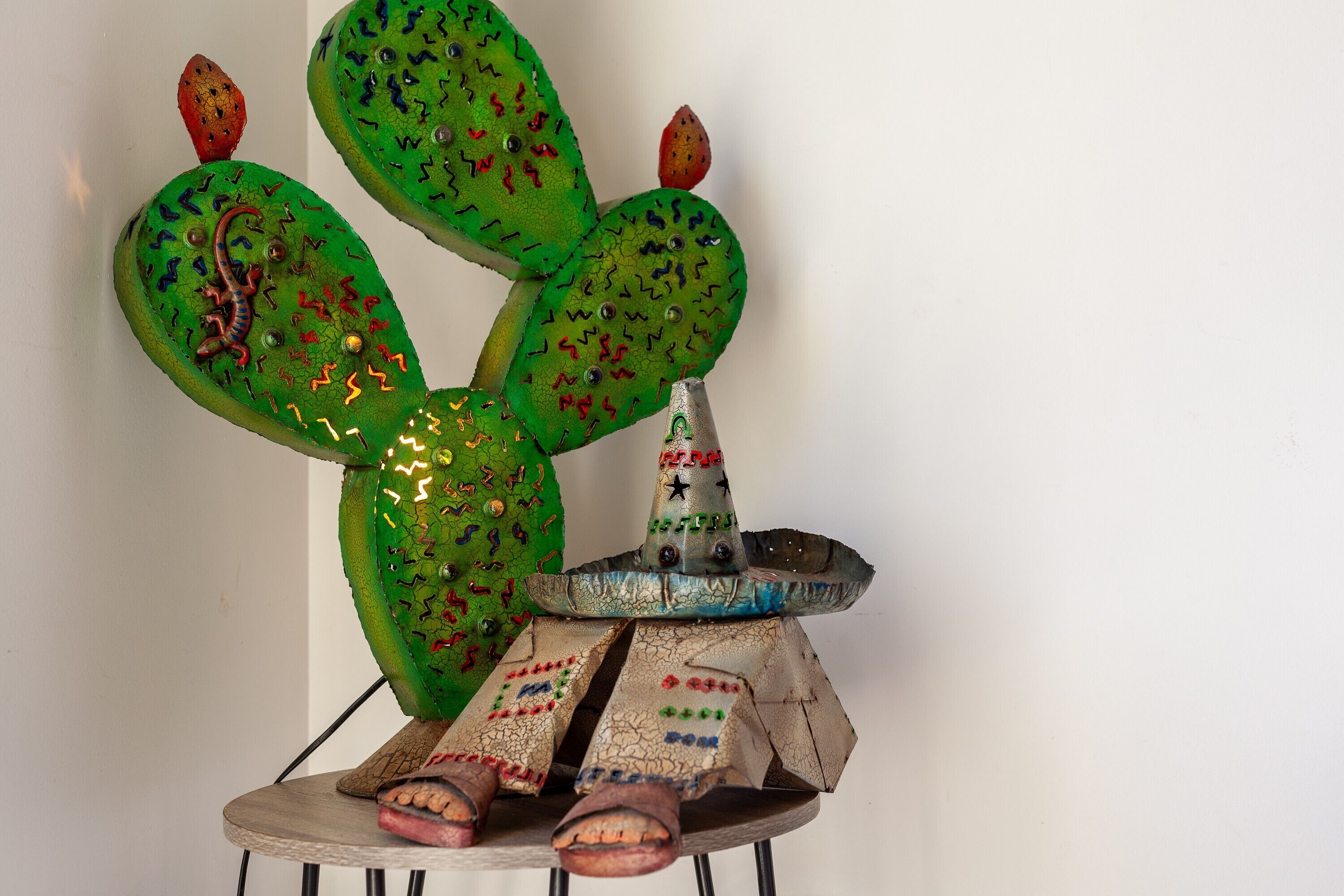 Una escultura de cactus con sombrero y sandalias.