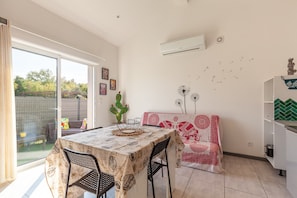 A dining area with a table and chairs, a cactus plant, and a view through a glass door. - Holiday Home 'Mexico' with Balcony and Air Conditioning (Saint-Mitre-les-Remparts)