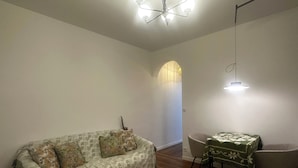 A living room with a sofa, a dining table with chairs, a chandelier, and a wall-mounted light fixture. - Pleasant stay in the heart of Paris, 4 people max (Paris)