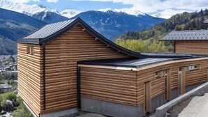 Una cabaña de madera con techo inclinado, al pie de montañas.