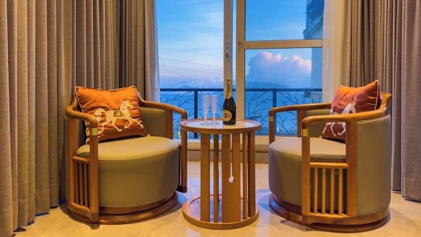 A room with two armchairs, a small round table, and a view of the sky through a large window. - the perch shimla (Shimla)