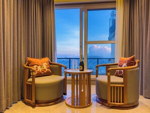 Una habitación con dos sillones, una mesita redonda y vistas del cielo a través de un ventanal grande.