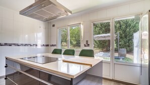 A modern kitchen with a central island, built-in appliances, and large windows offering a view of the outdoors.