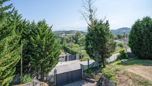 A residential area with a gated entrance, trees, and a view of distant hills.
