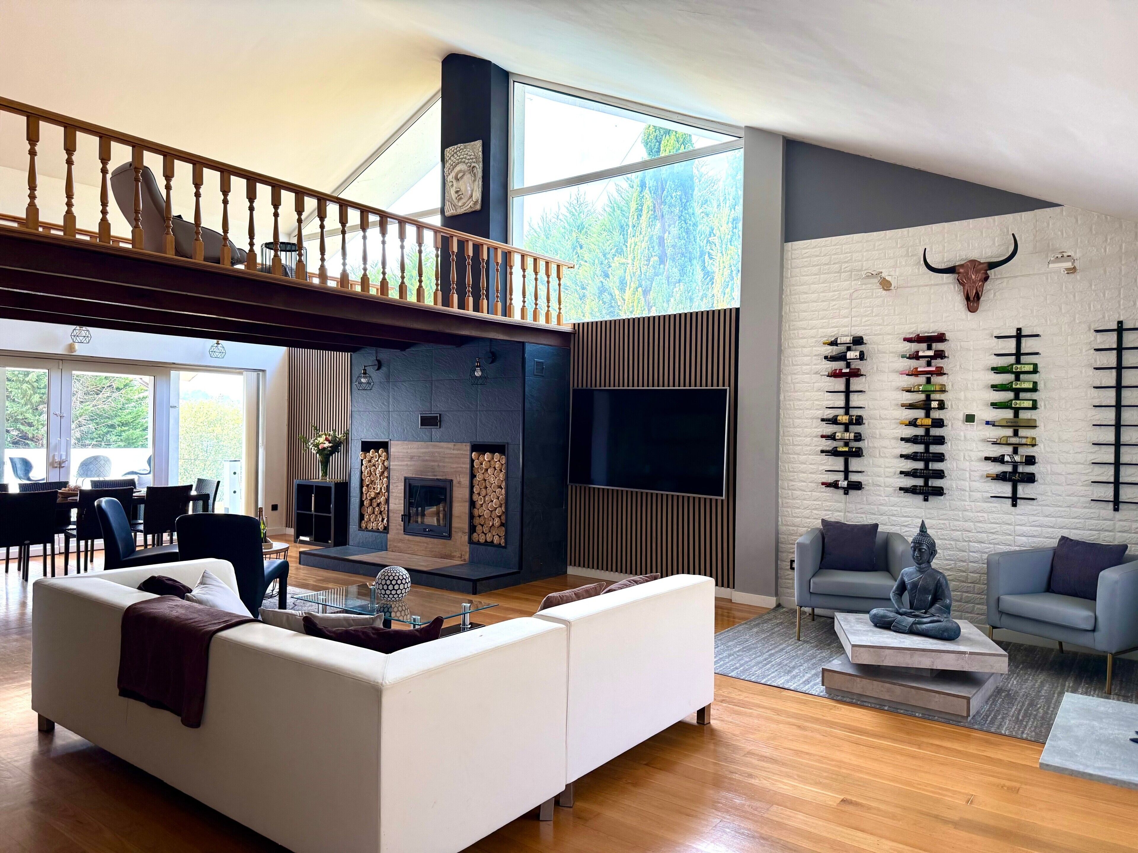 Een moderne woonkamer met een open haard, een ingebouwde wijnrek en een Boeddhabeeld.