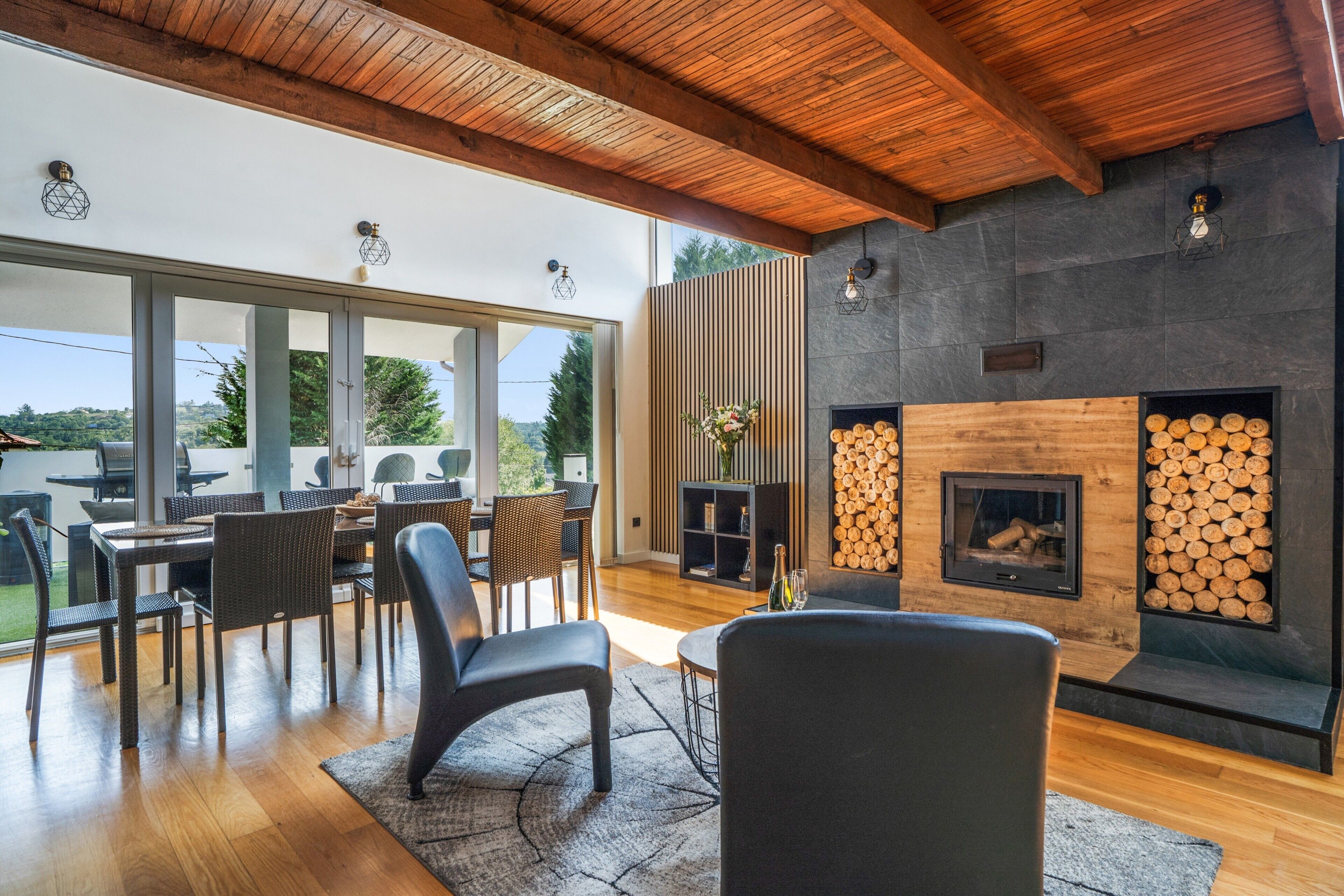 Een moderne woonkamer met een open haard, eethoek en grote ramen.