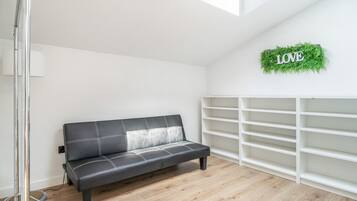 En moderne stue med en sort lædersofa, et hvidt indbygget reolsystem og et skilt med ordet 'LOVE' på væggen.