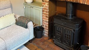 A living room with a brick fireplace, a sofa, a lamp, and a small table. - Charming countryside cottage near Canterbury, Kent (Bekesbourne)