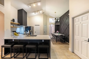 A modern kitchen with a large island, bar stools, and a dining area with a table and chairs.