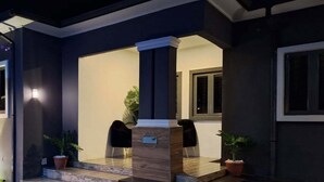 A modern reception area with a wooden reception desk, two black chairs, and potted plants. - NPJ Luxury Apartment  (Uyo)
