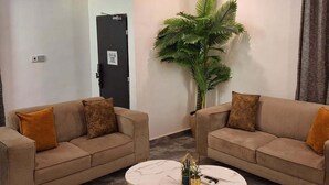 A modern living room with two sofas, a coffee table, and a large potted plant. - NPJ Luxury Apartment  (Uyo)