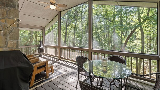 Un espace extérieur abrité, doté d’une terrasse en bois, d’une table en verre et de chaises.