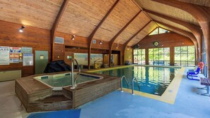 Une piscine intérieure en bois, dotée d’un jacuzzi, d’un espace dégagé autour de la piscine et offrant une vue sur l’extérieur.
