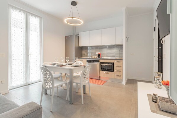 A modern kitchen with white cabinetry, a built-in oven, and a coffee machine.