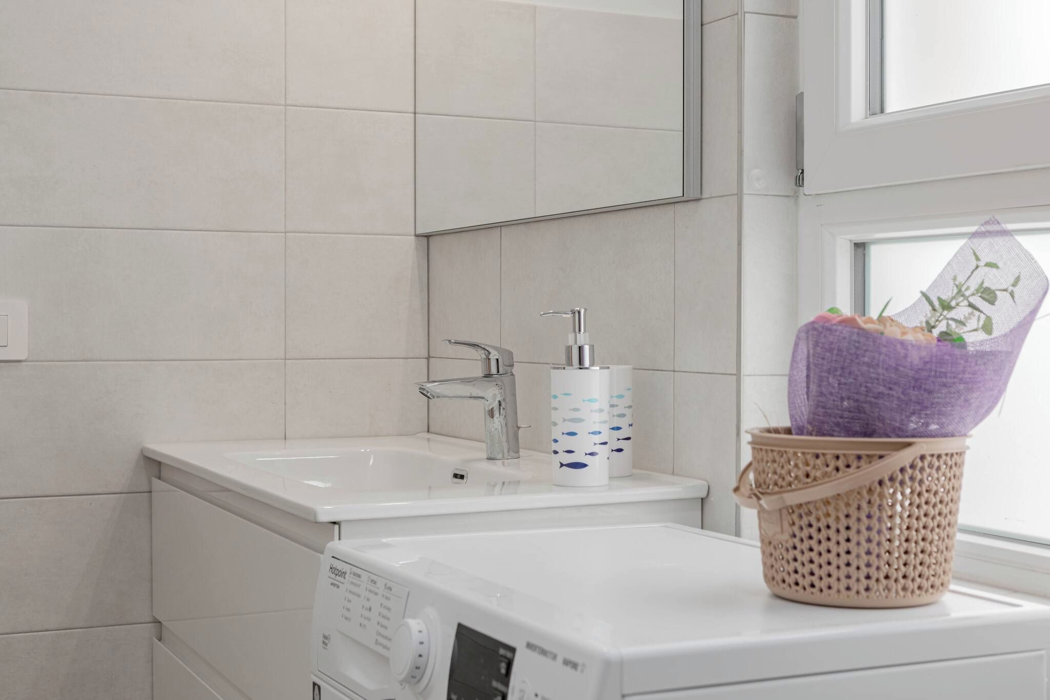 Une salle de bain avec un lavabo blanc, un miroir et un lave-linge.