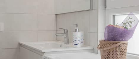 A bathroom with a white sink, a mirror, and a washing machine.