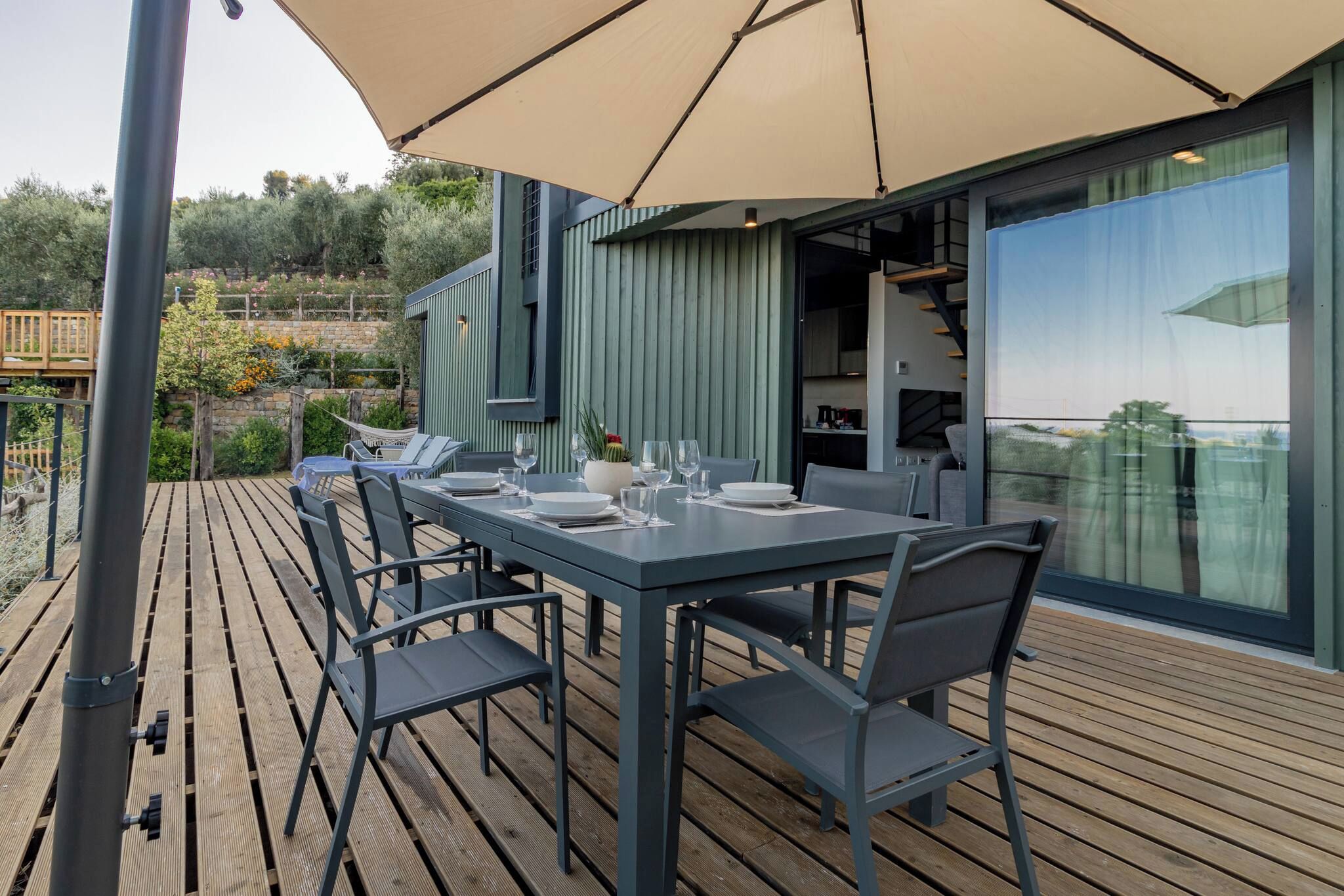 Ein Essbereich im Freien mit einem Tisch für vier Personen, umgeben von Stühlen, auf einer Holzterrasse.
