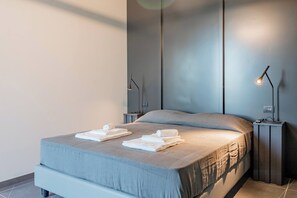 Een moderne slaapkamer met een bed, twee nachtkastjes en twee wandlampen.