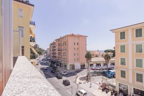 Vista de una calle con edificios de varios pisos, cielo despejado y coches estacionados.