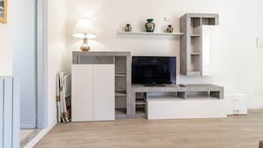 A modern living room with a flat-screen TV, built-in shelves, and a lamp.