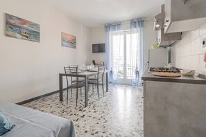 A compact living space with a dining area, kitchenette, and a large window with curtains.