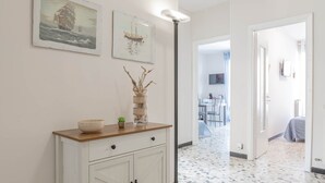 Ein Flur mit einem weißen Schrank, einer Stehlampe und zwei gerahmten Kunstwerken an der Wand.