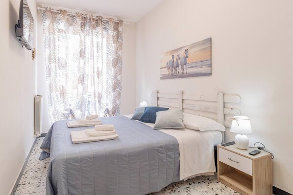 A bedroom with a bed, a nightstand, a lamp, and a painting on the wall.