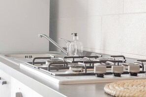 A kitchen with a gas stove, stainless steel appliances, and a white tiled backsplash.
