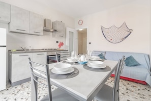A modern kitchen with a dining table set for four, a sofa, and a decorative wall hanging.