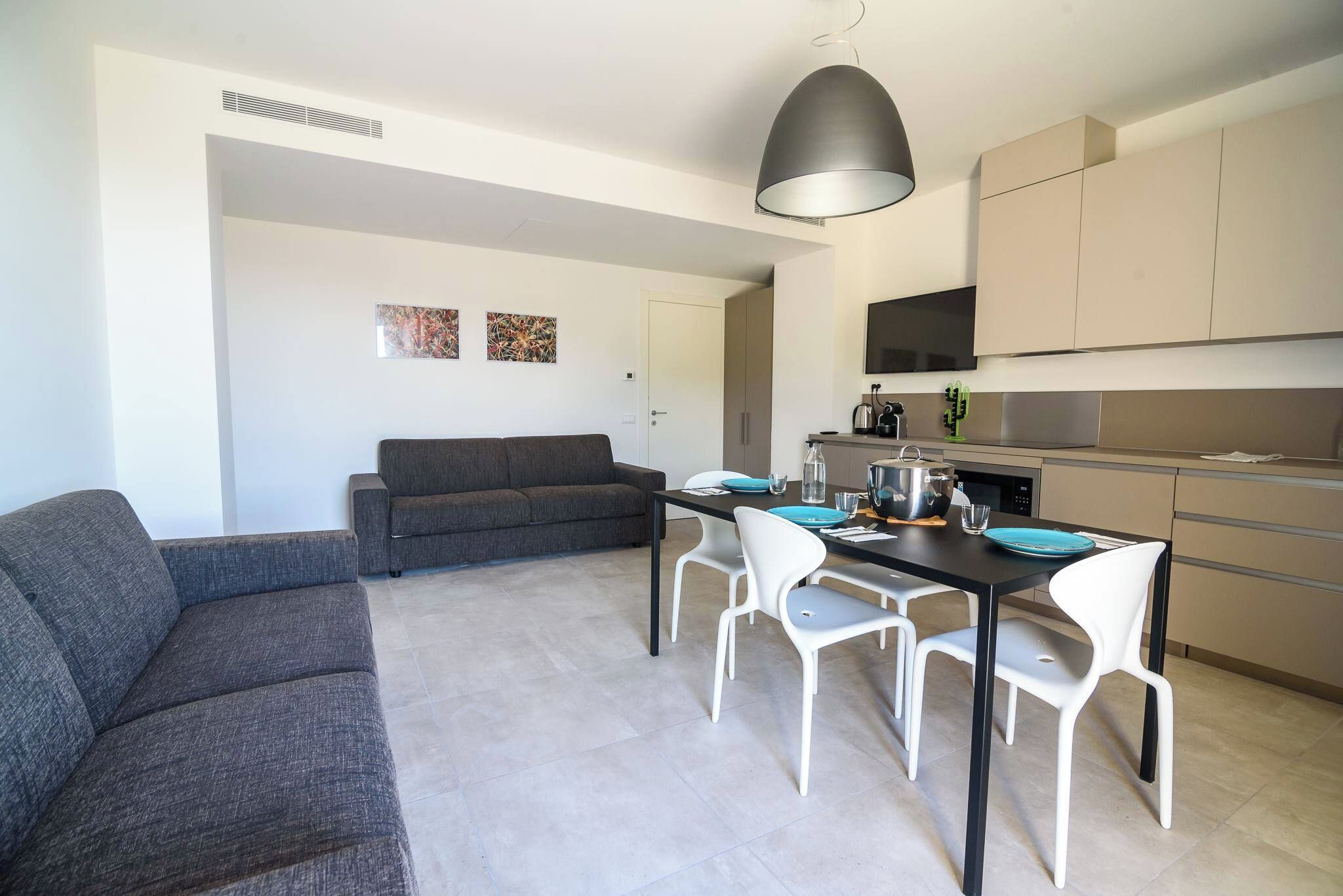 Un espace de vie moderne comprenant un canapé, une table à manger, des chaises et un coin cuisine.