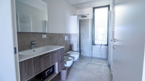A modern bathroom with a large mirror, a sink, a toilet, and a shower area.