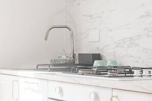 A modern kitchen with a stainless steel faucet, a dish soap dispenser, and a gas stove with a range hood.