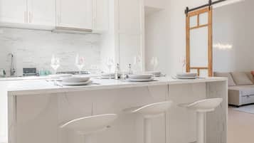 Een koelkast, een oven, een kookplaat, kookgerei, borden en bestek