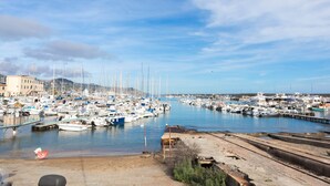 Un port de plaisance où sont amarrés de nombreux bateaux, une plage de sable et un ciel dégagé.