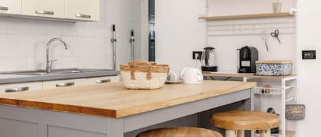 A modern kitchen with a wooden countertop, a built-in sink, and a coffee machine.