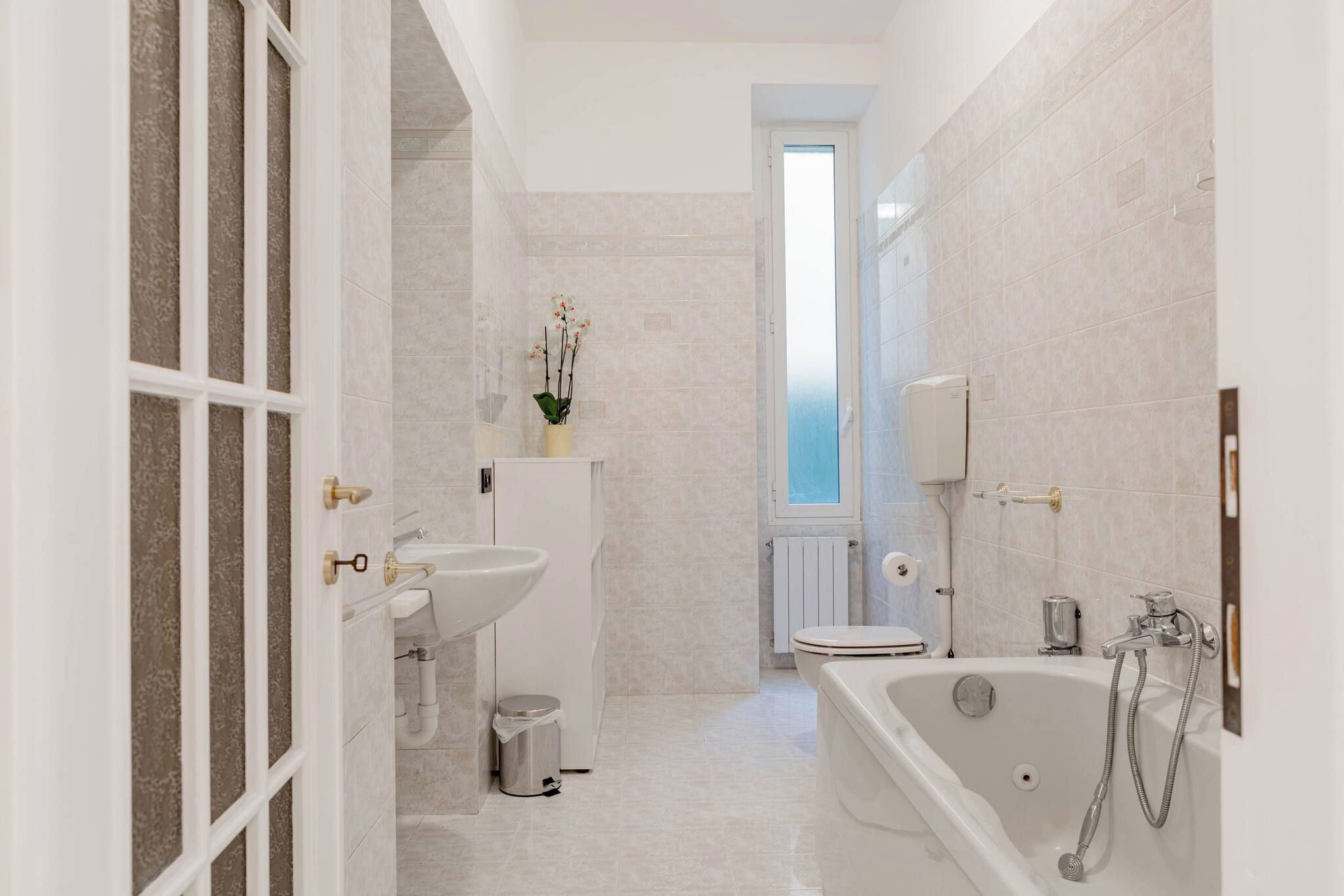 Un baño moderno con bañera, inodoro, lavamanos y ventana.