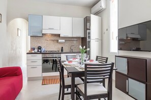 A modern kitchen with white cabinets, a dining table set for two, and a red chair.
